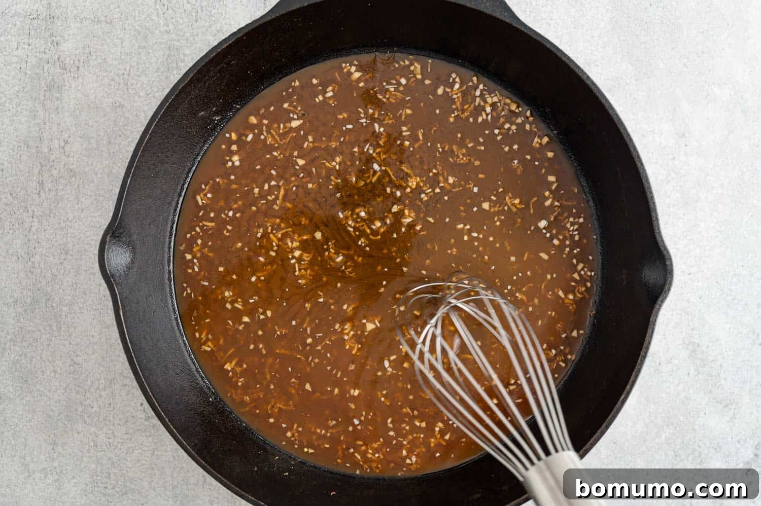 Homemade teriyaki sauce simmering and thickening in a frying pan, transforming into a glossy glaze.
