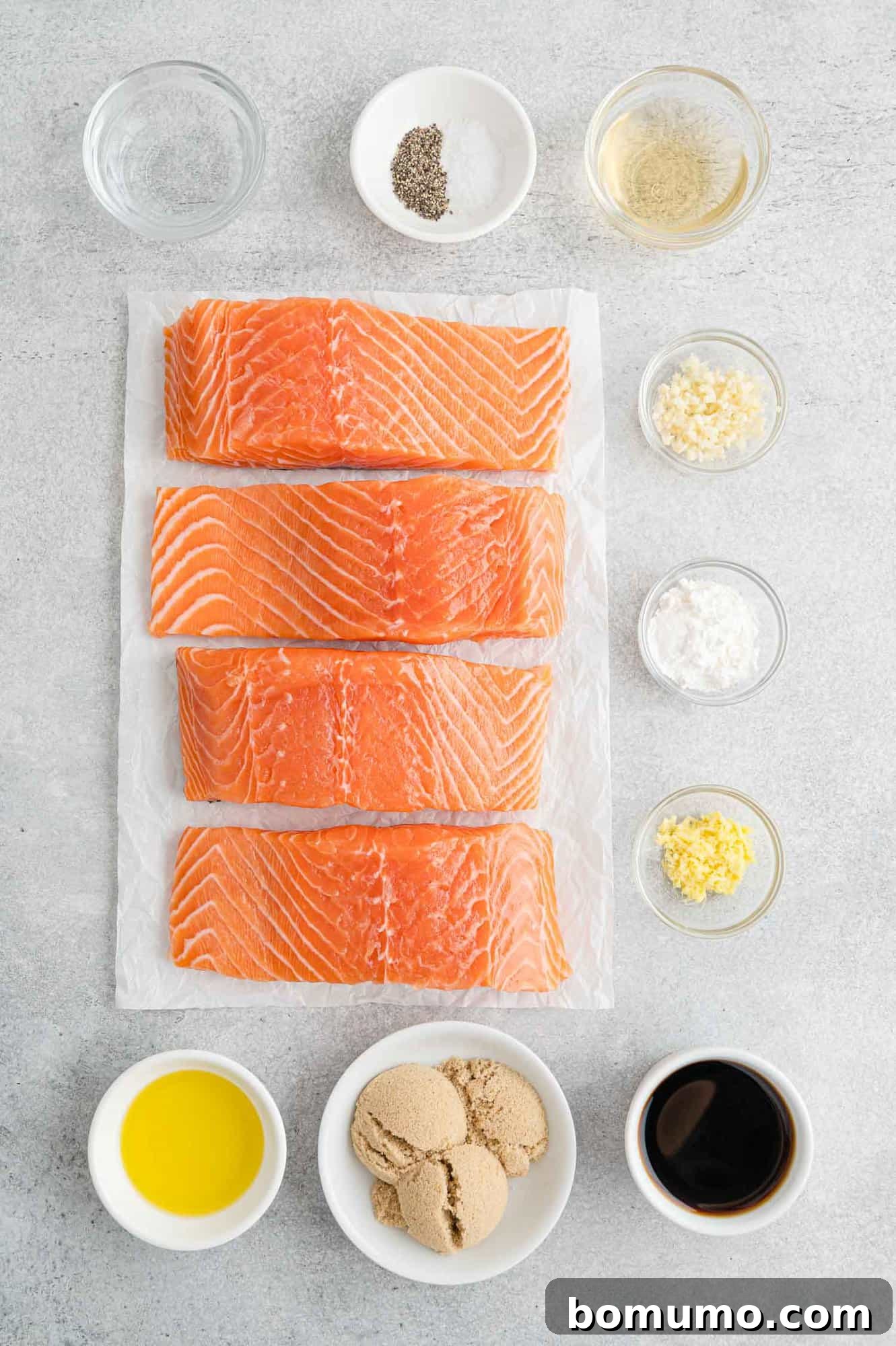 All the fresh ingredients for homemade teriyaki salmon laid out on a kitchen counter, including salmon fillets, ginger, garlic, and sauce components.