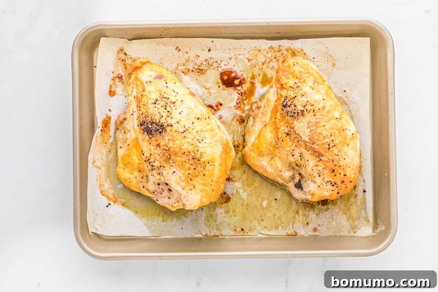 Two golden-brown, perfectly roasted bone-in chicken breasts on a sheet pan, ready to be served or shredded.