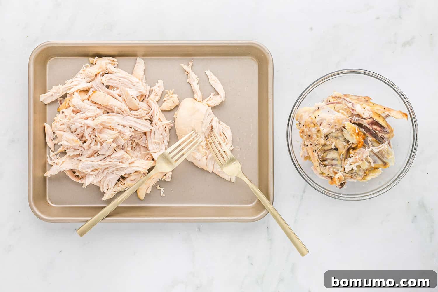Cooked chicken breast being shredded with two forks on a cutting board, perfect for meal prep.
