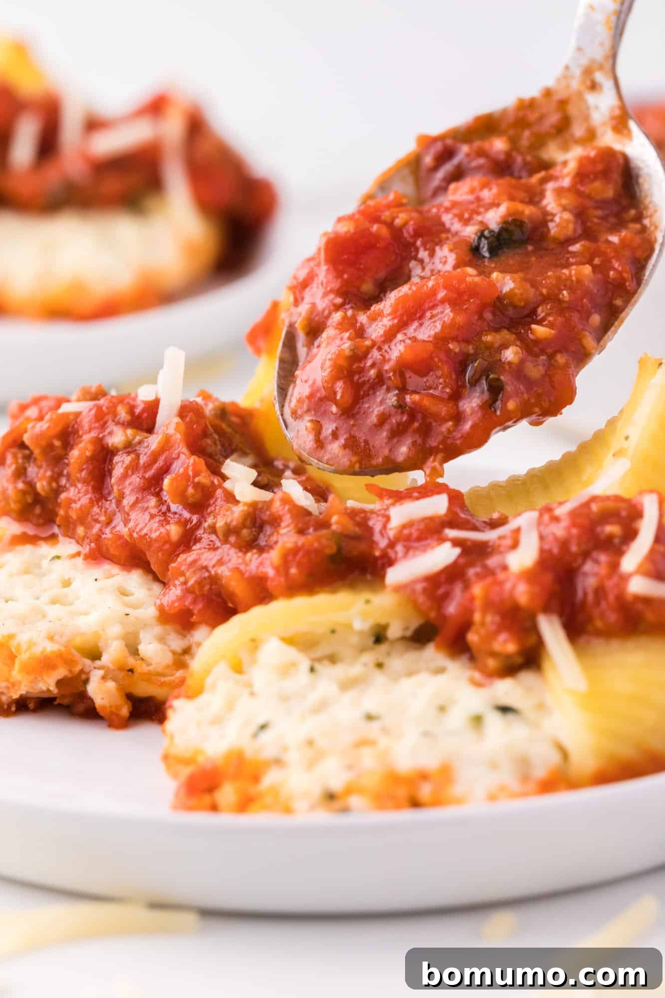 Savory Meat-Filled Jumbo Shells 3 A large serving spoon ladling rich, homemade meat sauce over perfectly cooked, cheese-stuffed jumbo shells arranged in a baking dish, ready for baking.