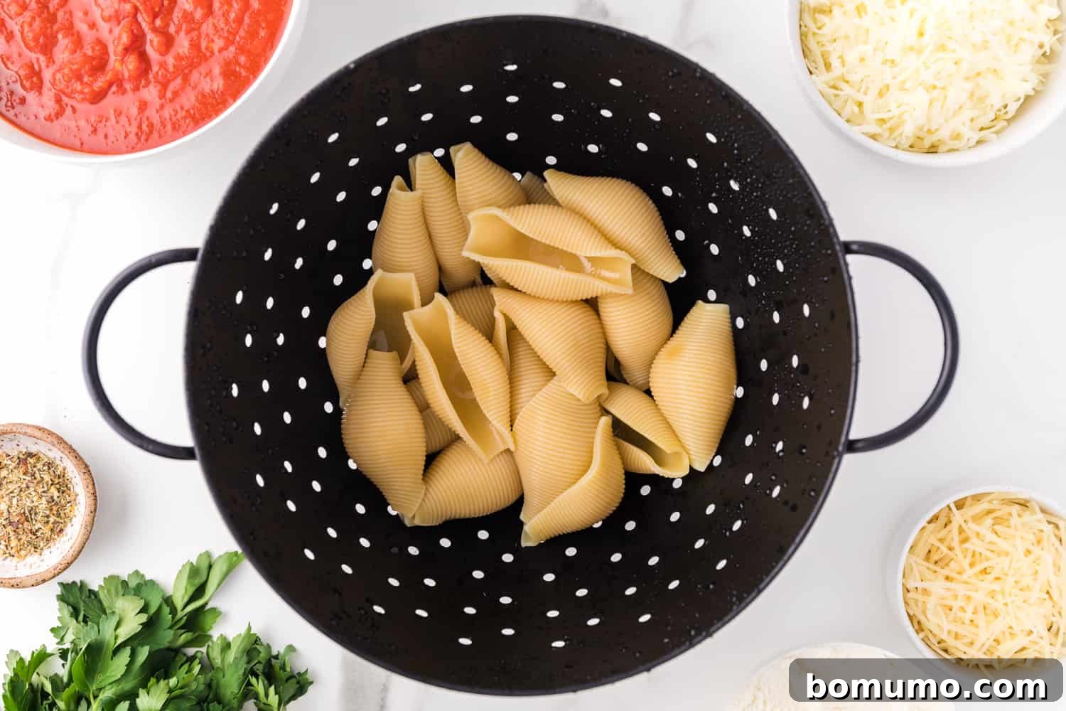 Savory Meat-Filled Jumbo Shells 5 Freshly cooked jumbo pasta shells resting in a colander after being drained, ready for the next step of filling.