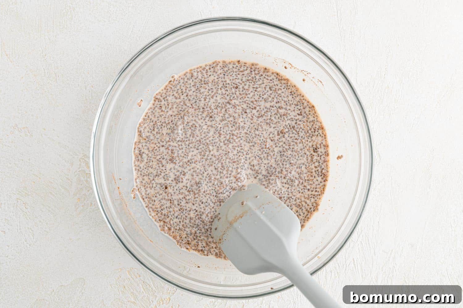 A spoon stirring the chia seed mixture in a bowl, showing the thickening process.