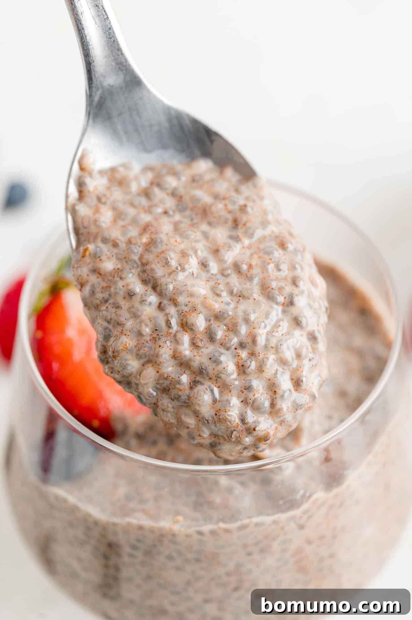 Close up of a spoon scooping creamy chia seed pudding, showing its texture.