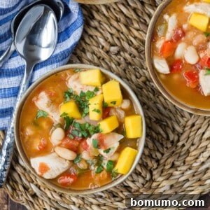 Jerk chicken chili, garnished with vibrant mango cubes and fresh cilantro.