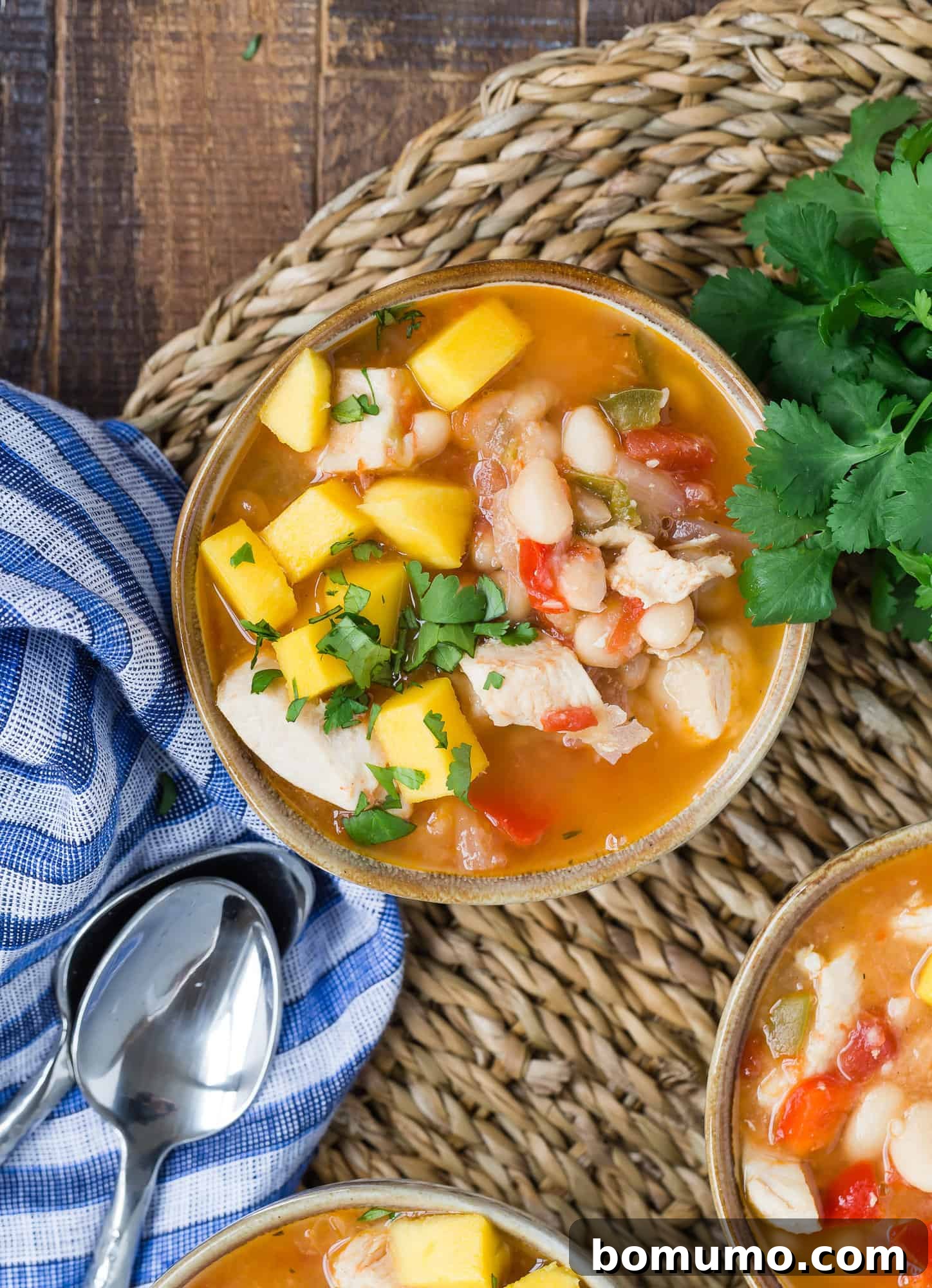 A bowl of Caribbean chicken chili, brimming with colorful vegetables and chicken, garnished with fresh herbs and a vibrant mix of ingredients.