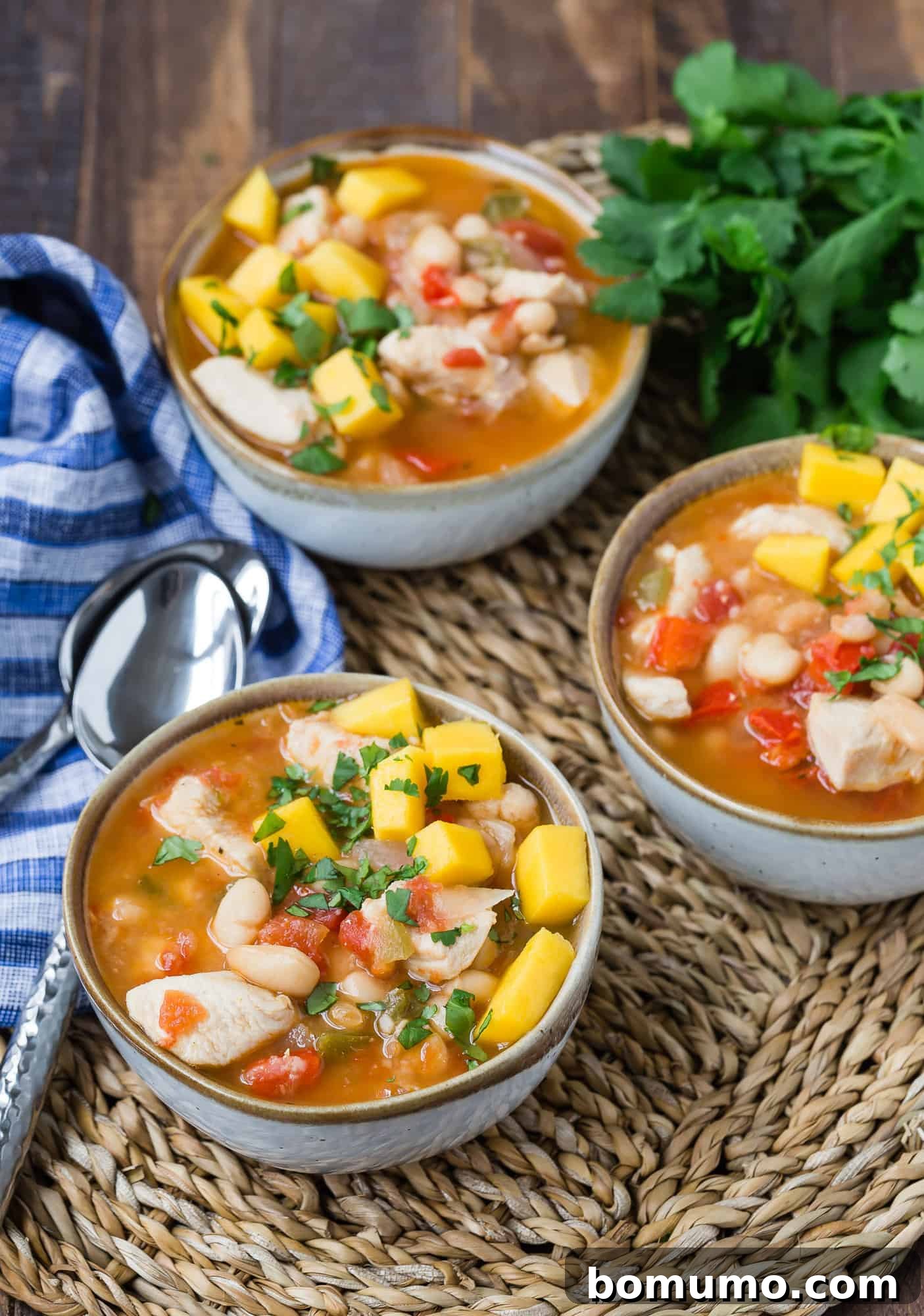 A serving of Caribbean chicken chili, generously topped with fresh diced mango, showcasing the vibrant flavors and fresh garnishes.