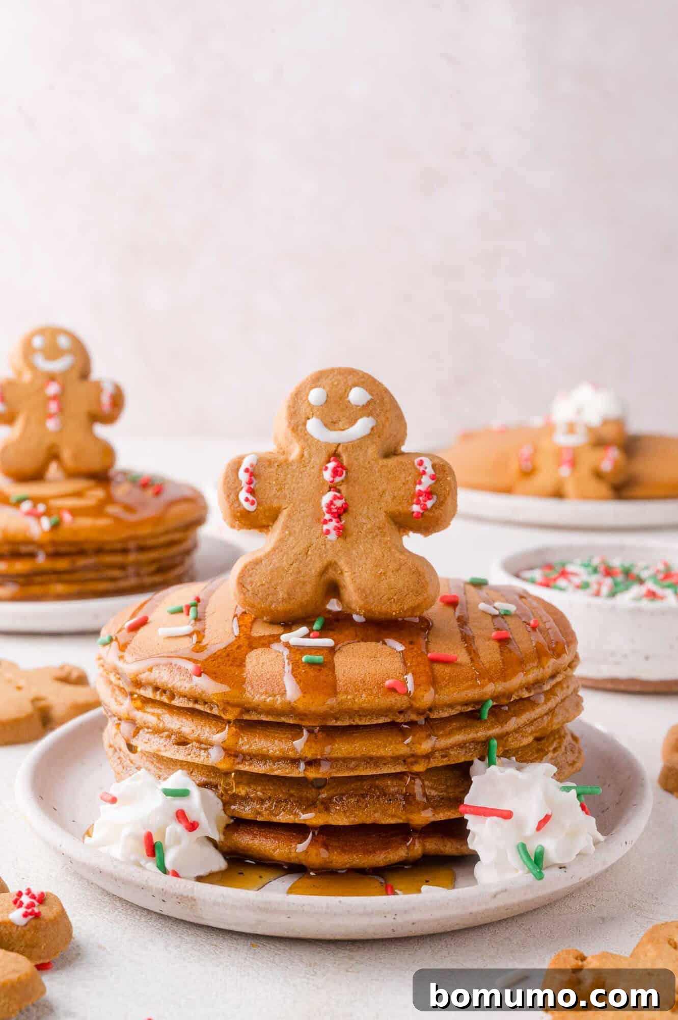 Gingerbread Bliss Pancakes 2 A delicious stack of gingerbread pancakes topped with syrup, whipped cream, sprinkles, and a festive gingerbread man cookie.