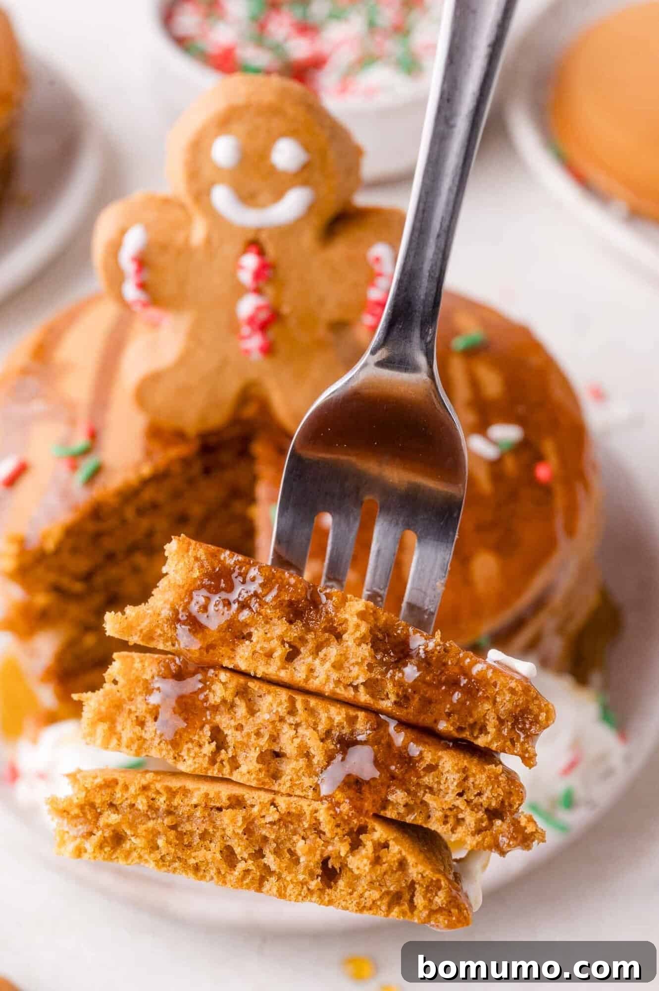 Gingerbread Bliss Pancakes 11 Fork holding a bite of stacked gingerbread pancakes with syrup.