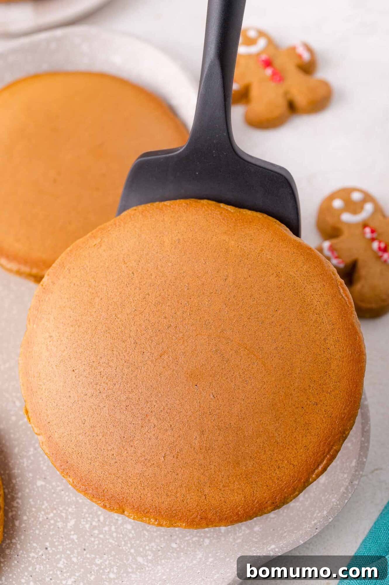 Gingerbread Bliss Pancakes 10 A spatula lifting a round, golden-brown pancake.