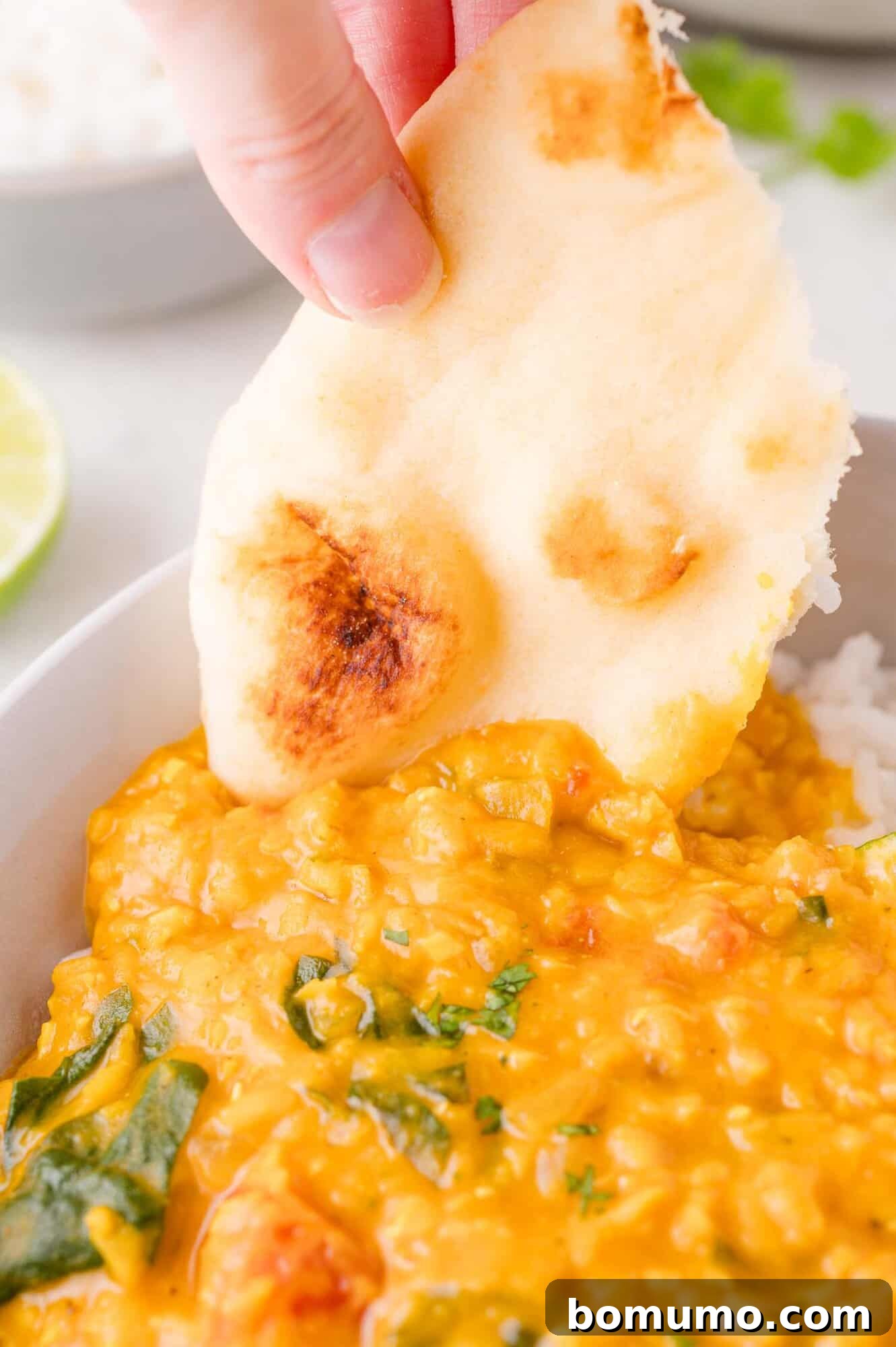 Dipping naan into red lentil curry