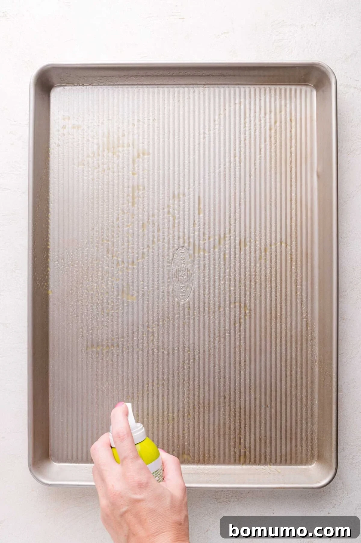 Spraying a baking sheet with nonstick cooking spray.