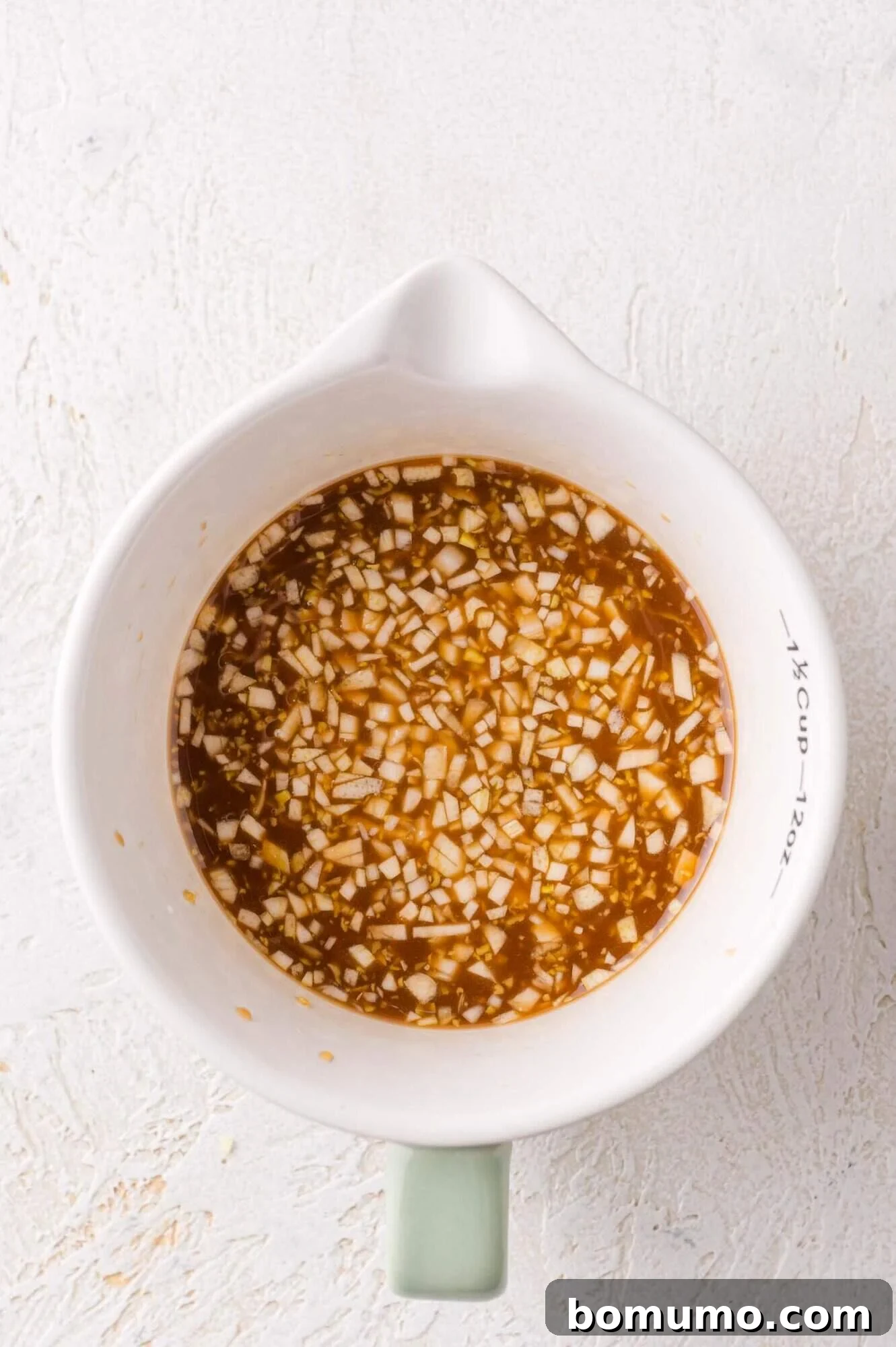 Teriyaki Sauce Mixture: A white measuring cup filled with uncooked teriyaki sauce.