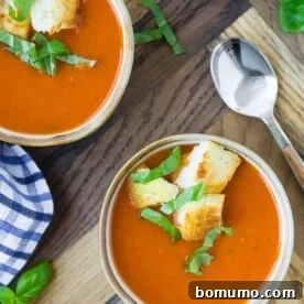 Overhead view of three small bowls of instant pot tomato soup, topped with croutons and fresh basil.