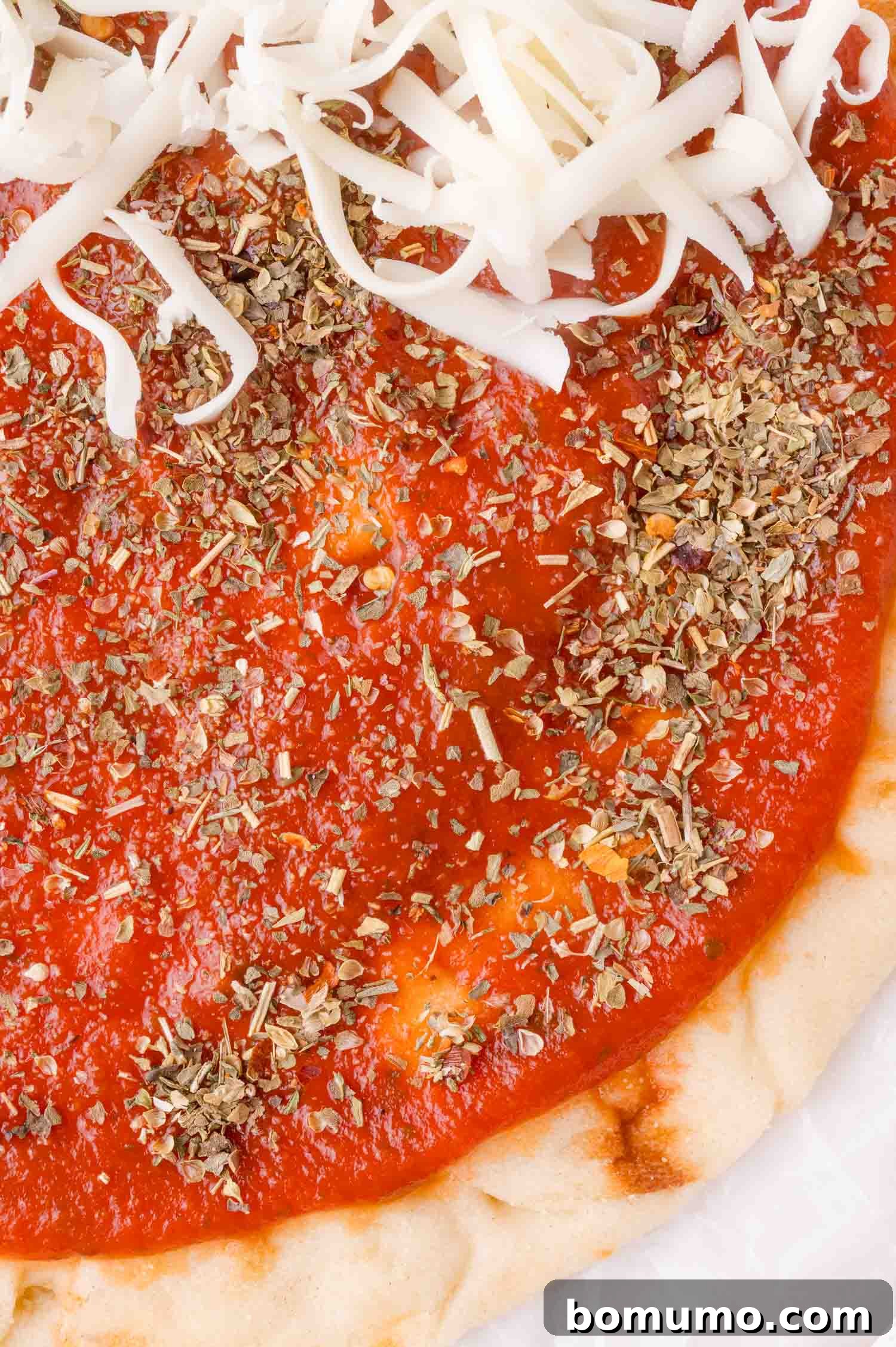 Pizza dough with sauce, cheese and pizza seasoning