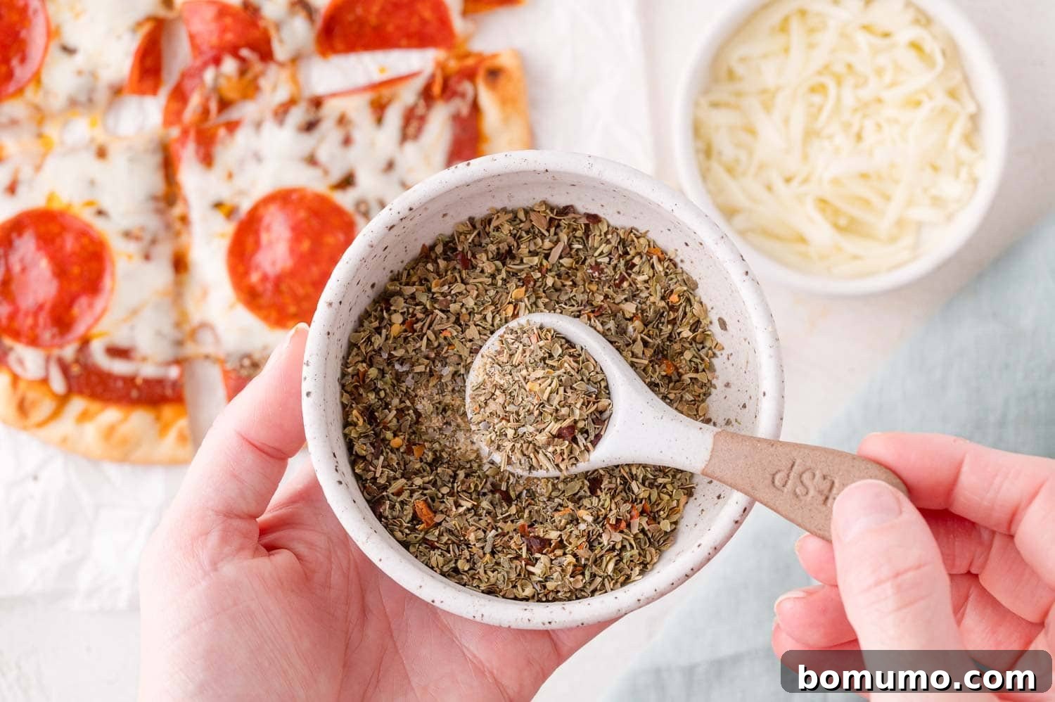 Hand holding bowl of pizza seasoning