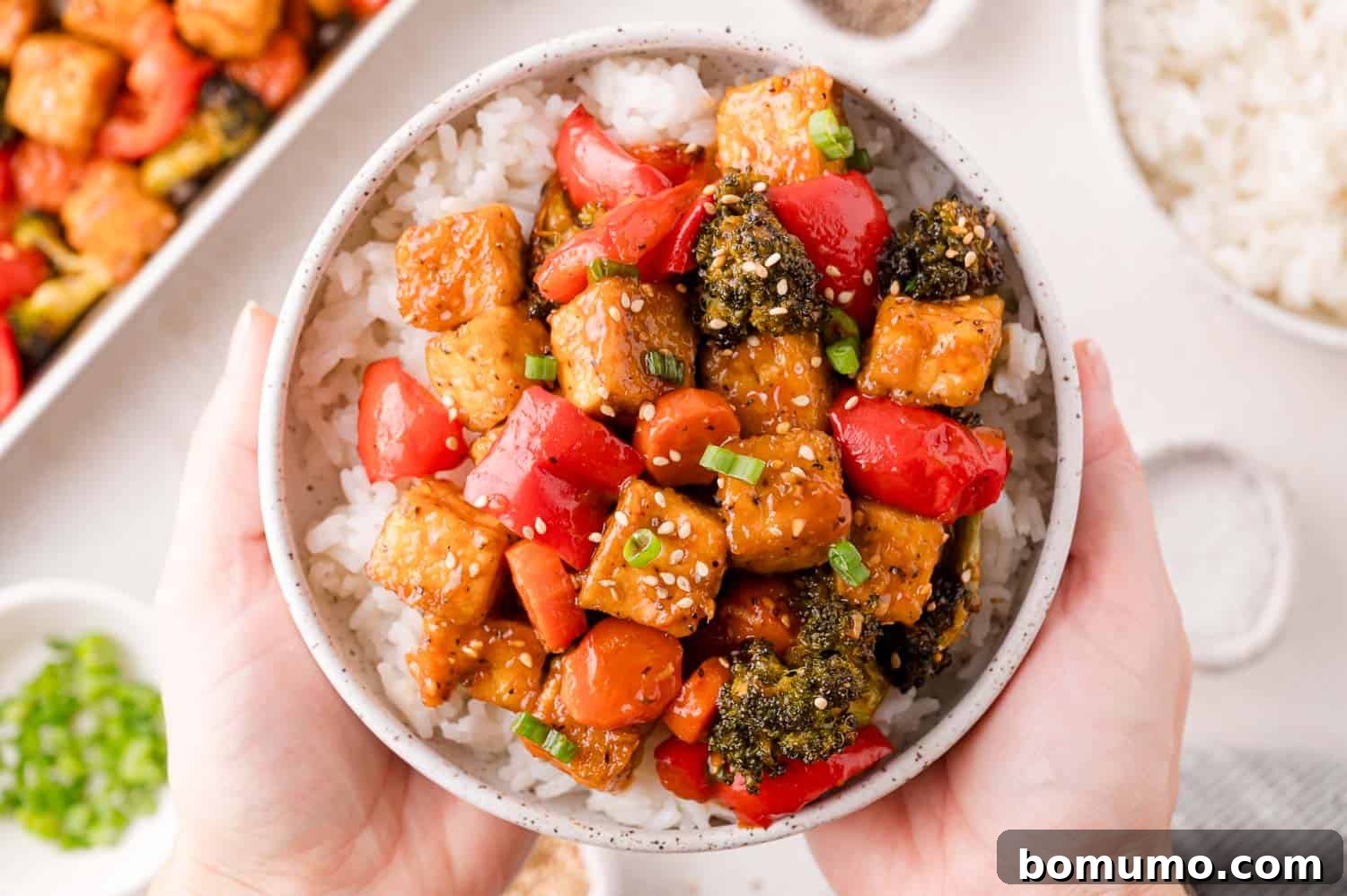 Bowl of rice topped with General Tso tofu and garnishes