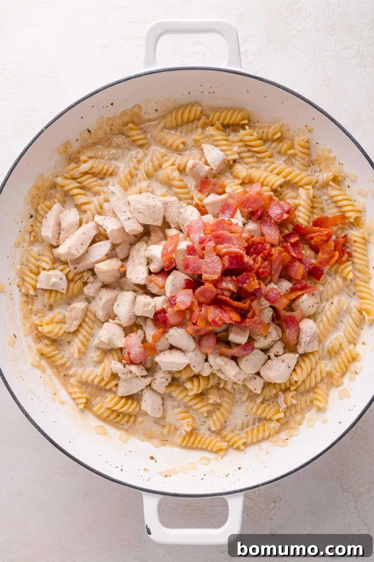 Cooking pasta and chicken with creamy sauce in white pot