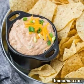 Bowl of creamy Mexicali dip surrounded by tortilla chips.