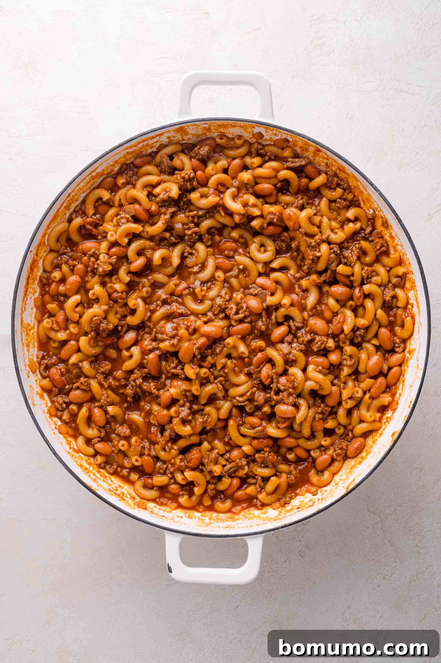Cooked macaroni, meat, and beans in tomato sauce.
