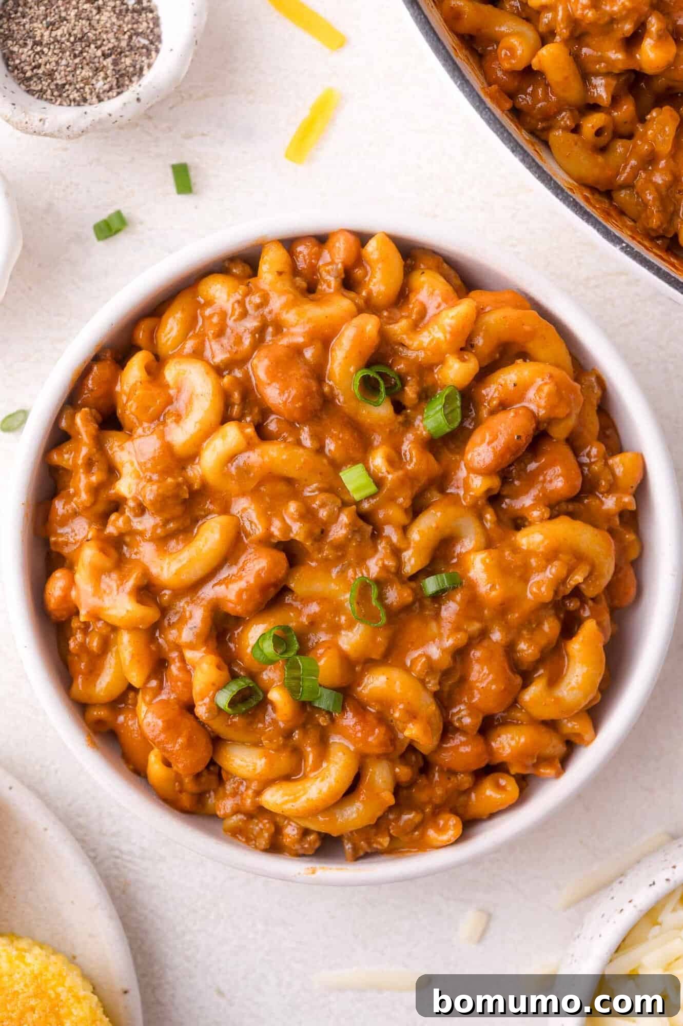Chili mac in a bowl with green onions.