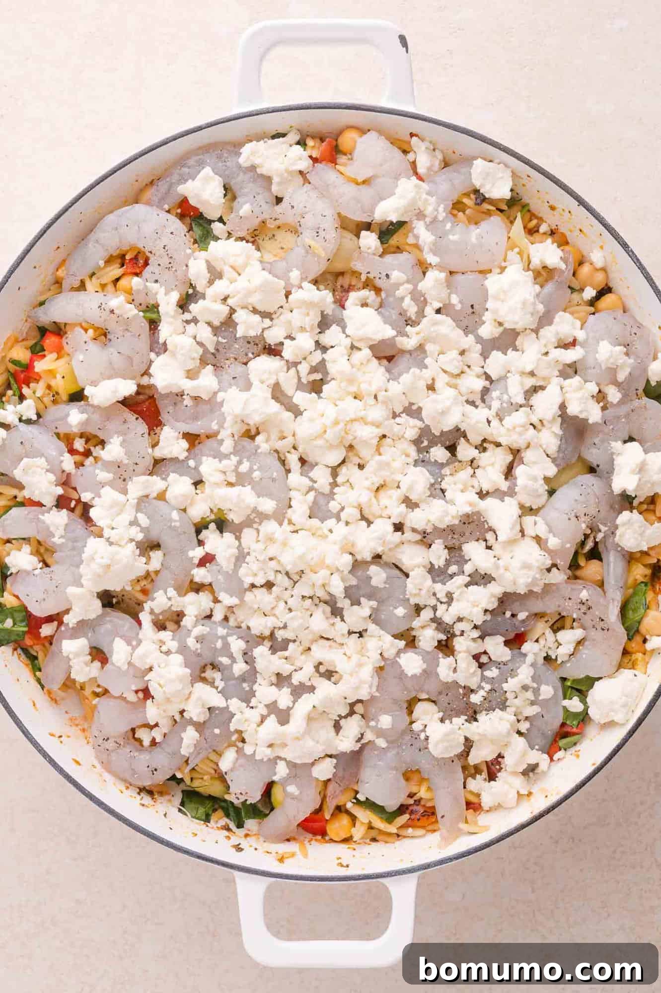 Arranging shrimp and feta over orzo
