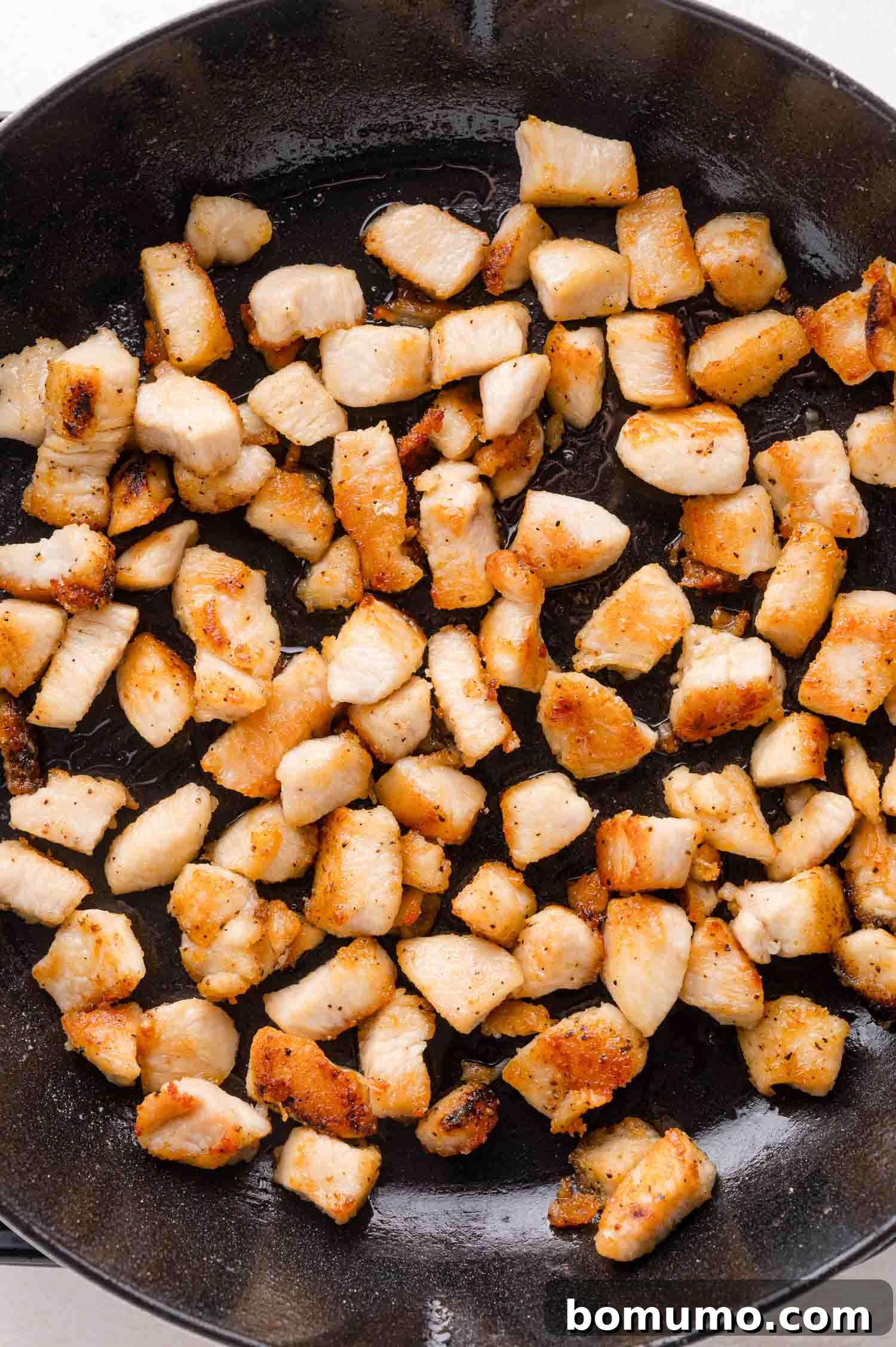 Cooking diced chicken breast in a frying pan.