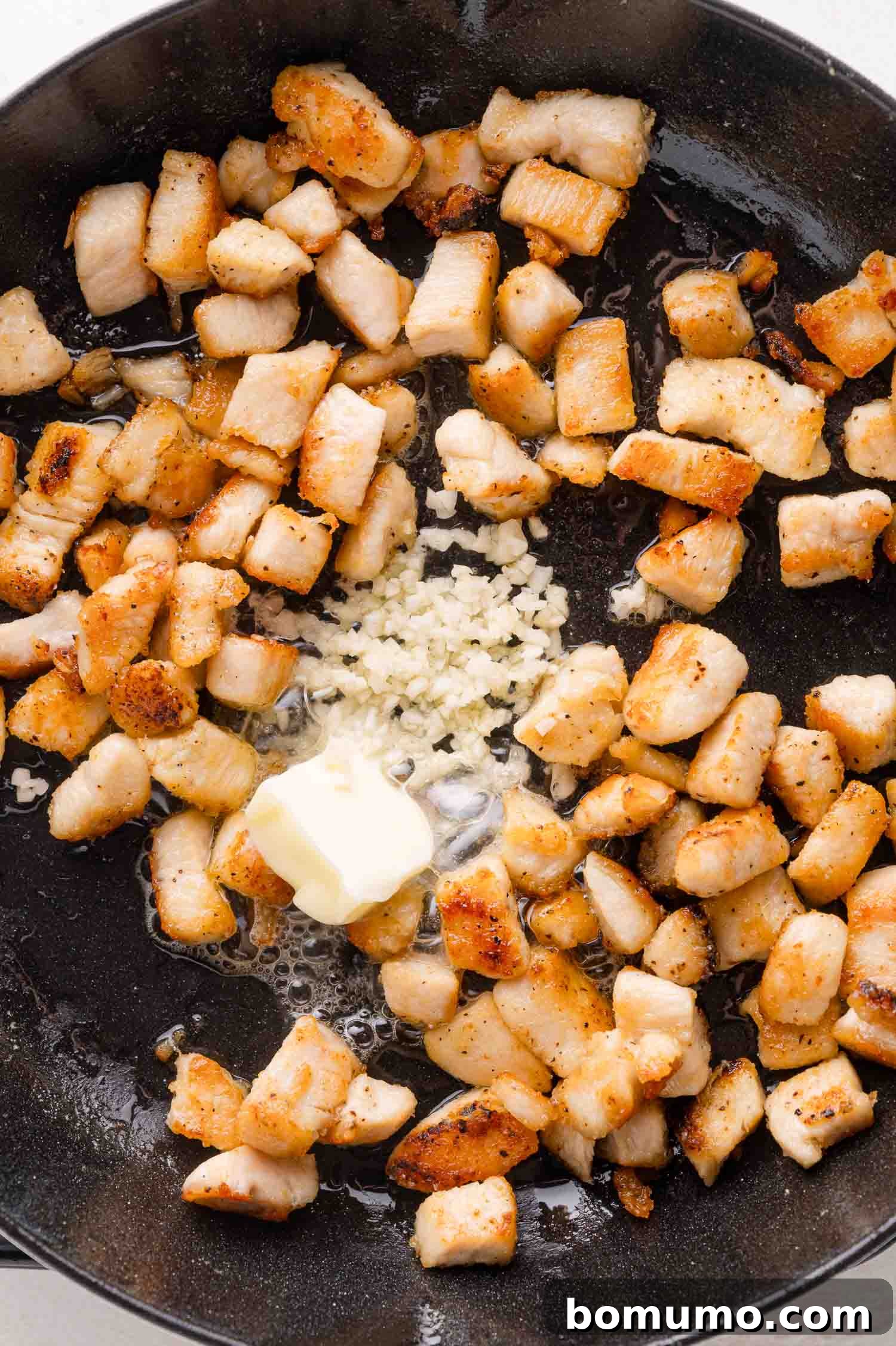 Add butter, garlic and chicken cubes in a black skillet.