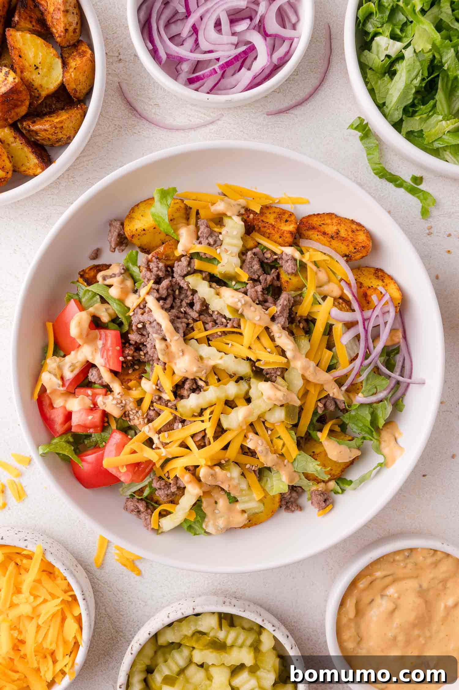Delicious Burger Bowl with ground beef, cheese, lettuce, and Big Mac sauce, surrounded by fresh toppings.