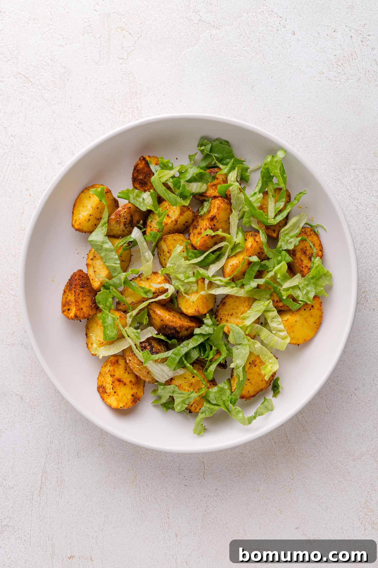 Roasted potatoes and lettuce in a bowl.