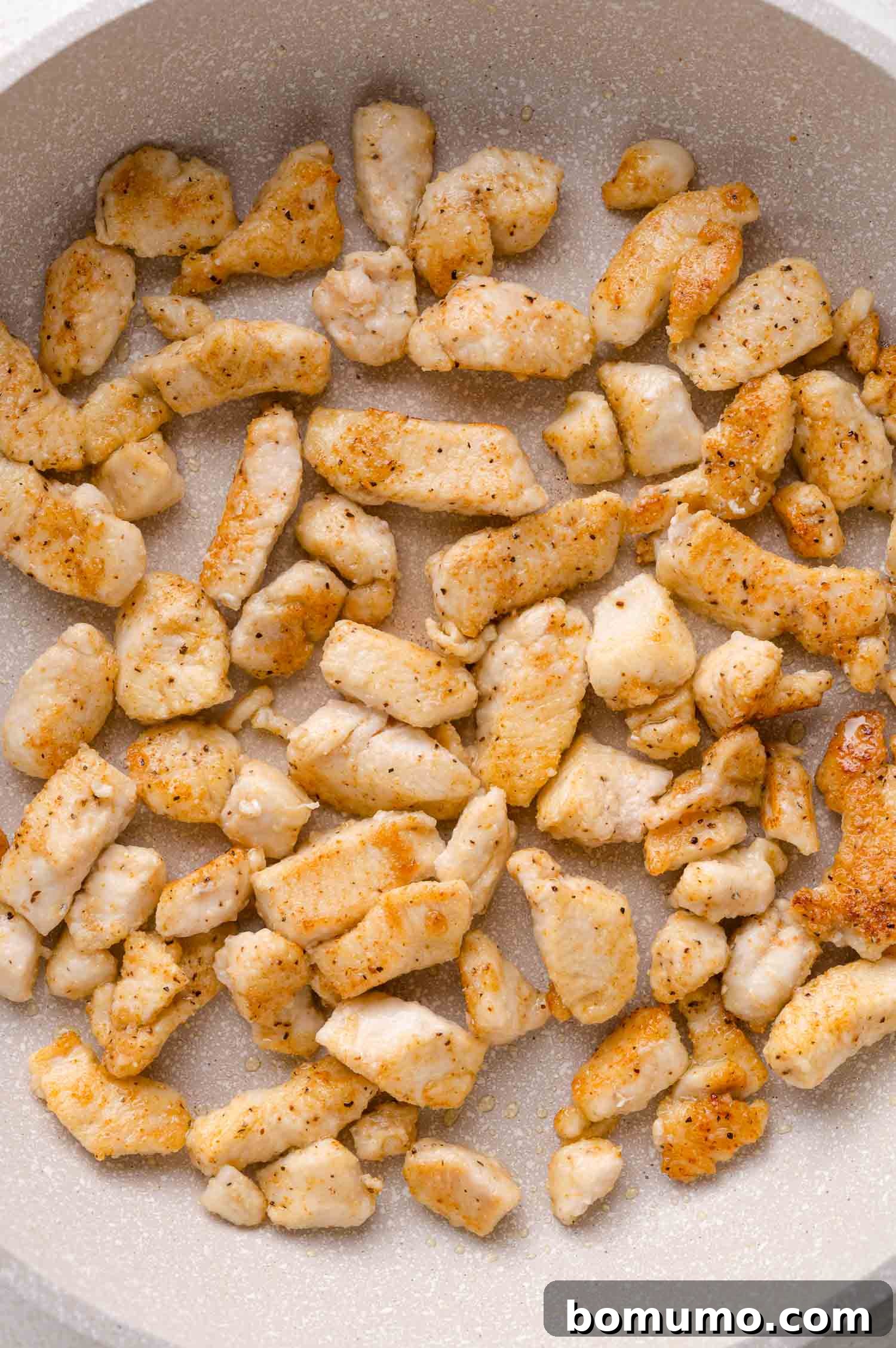 Cooked, seasoned chicken pieces in a frying pan.