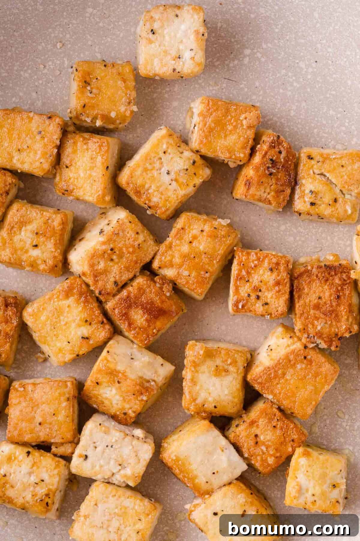 Golden brown cubes of seasoned and pan-fried tofu arranged in a pan.