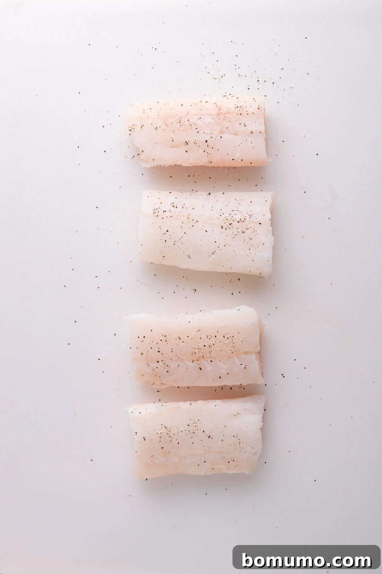 Golden Lemon Butter Cod 4 Four raw cod fillets seasoned with salt and pepper ready for cooking.
