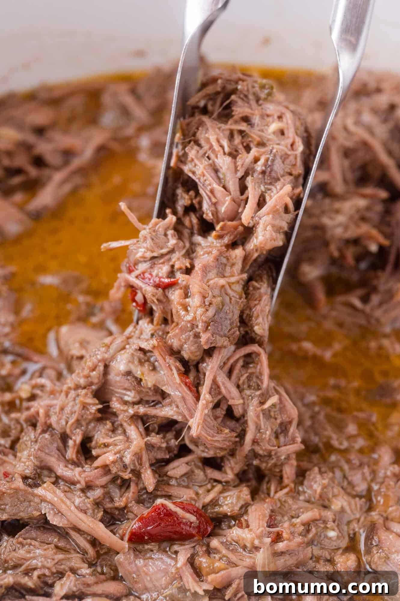 Effortless Shredded Barbacoa 13 A spoonful of the finished shredded beef, soaked in the rich cooking juices.
