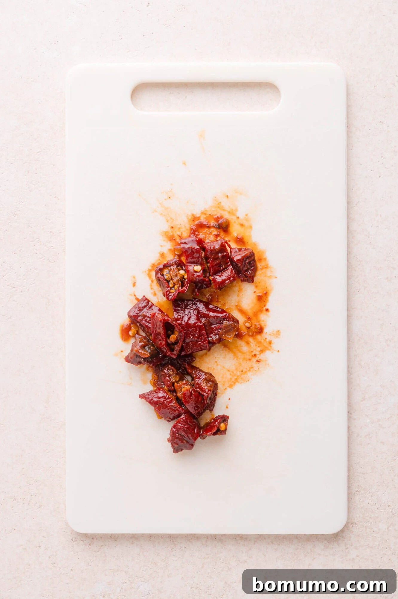 Effortless Shredded Barbacoa 6 Finely chopped chipotle peppers on a white cutting board, ready to be added to the slow cooker.