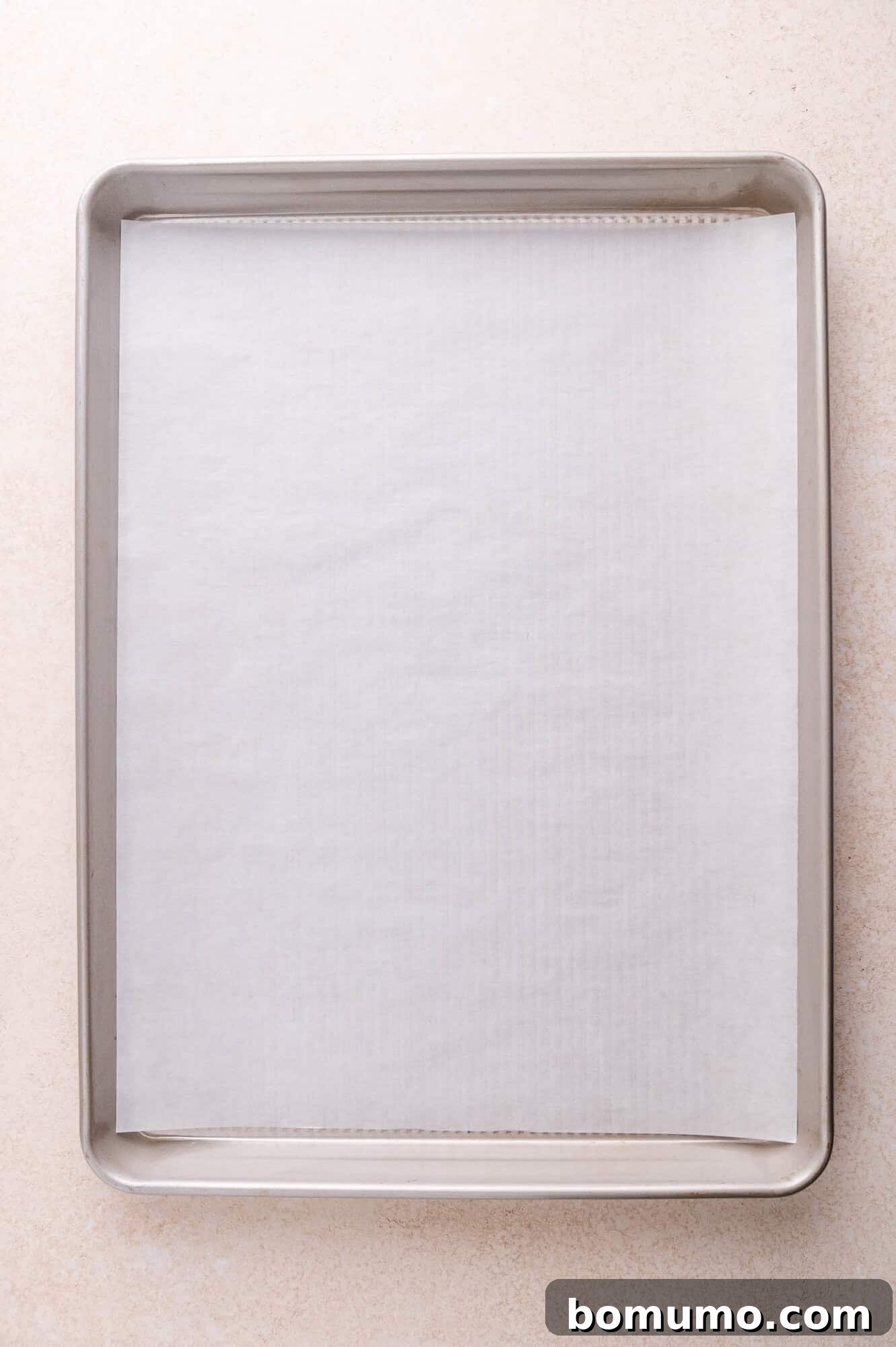 A baking sheet lined with a sheet of parchment paper on a light-colored surface.