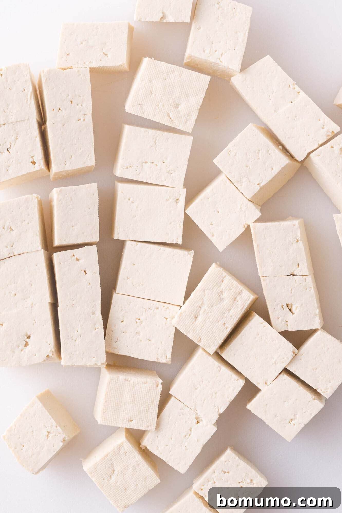 Cubes of plain tofu arranged on a white surface.