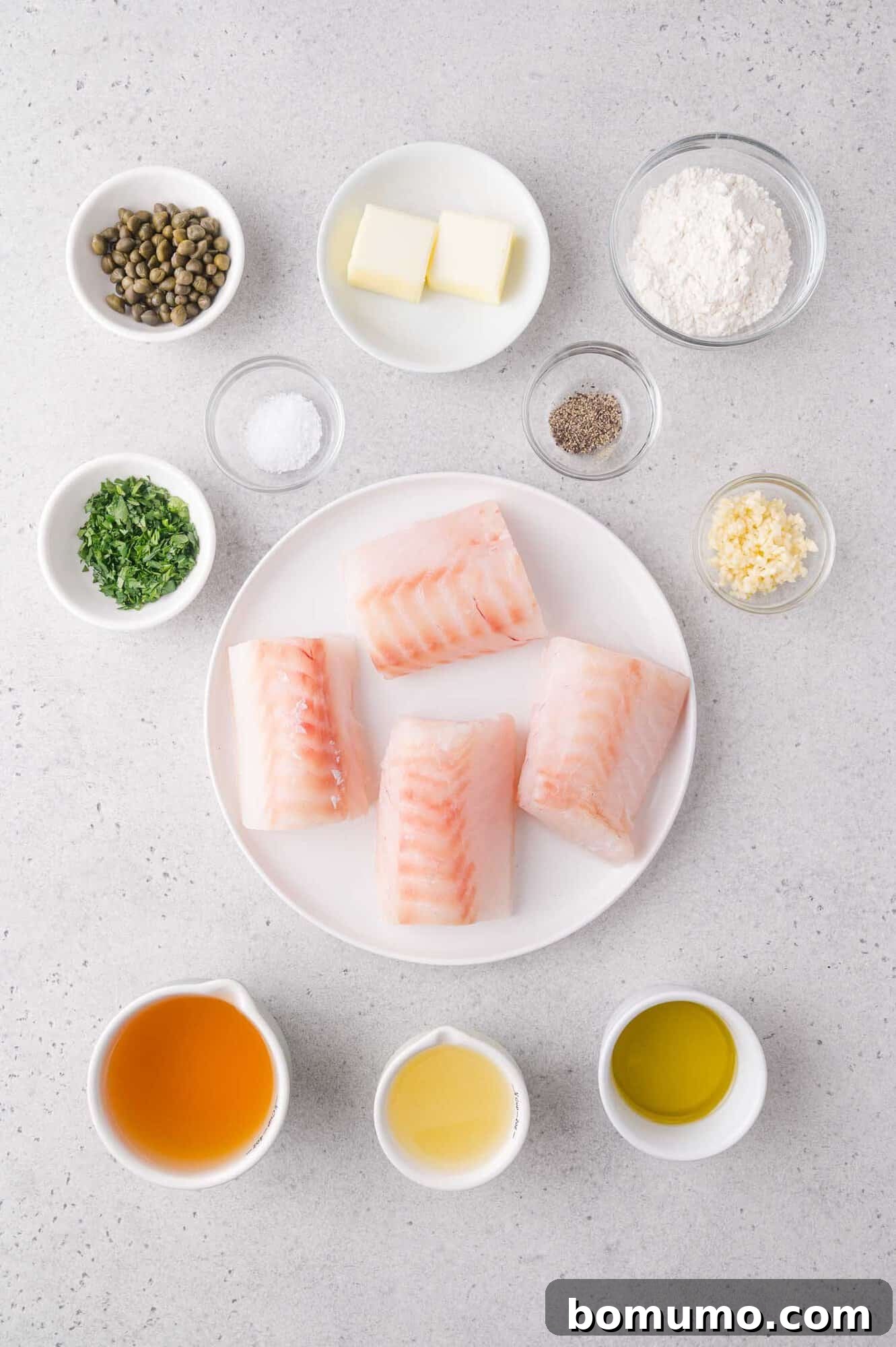 Lemon-Caper Cod Piccata 3 Four raw cod fillets on a plate with small bowls of ingredients.
