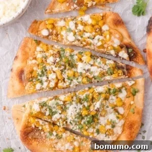 Flatbread topped with corn, crumbled cheese, and chopped cilantro, sliced into pieces and arranged on parchment paper.