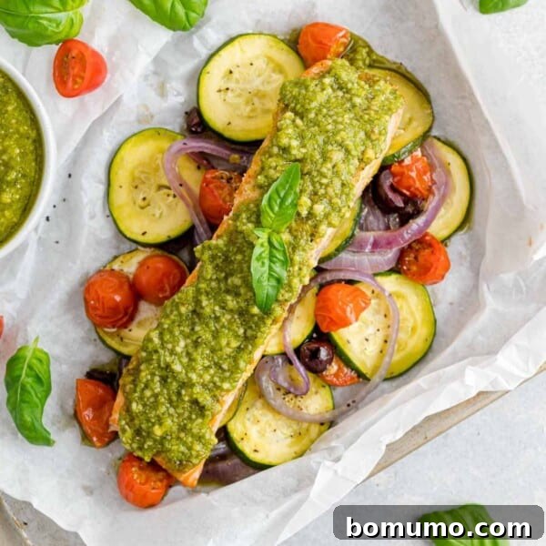 Vegetables and salmon topped with pesto in a parchment paper packet.