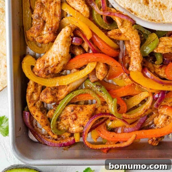 Overhead view of sheet pan fajitas with chicken, peppers, and onions.