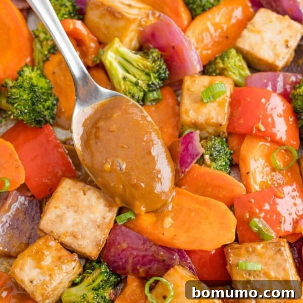 Peanut sauce being added to tofu sheet pan dinner.