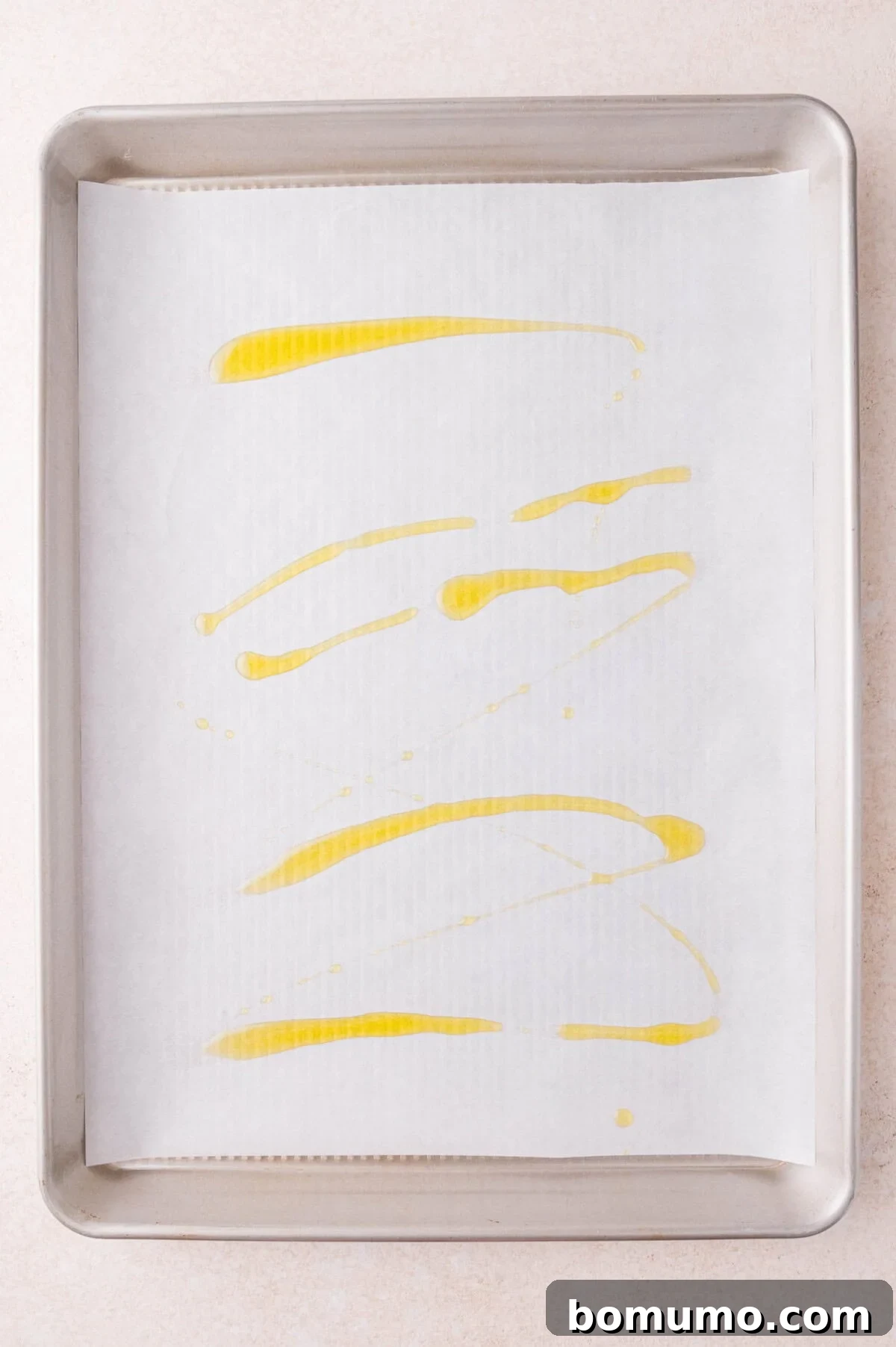 A baking sheet lined with parchment paper is drizzled with olive oil.