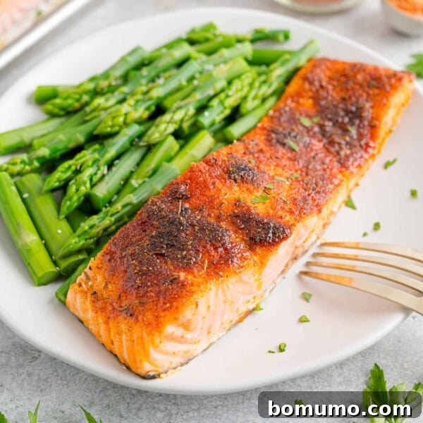 Broiled salmon on a white plate with steamed asparagus.