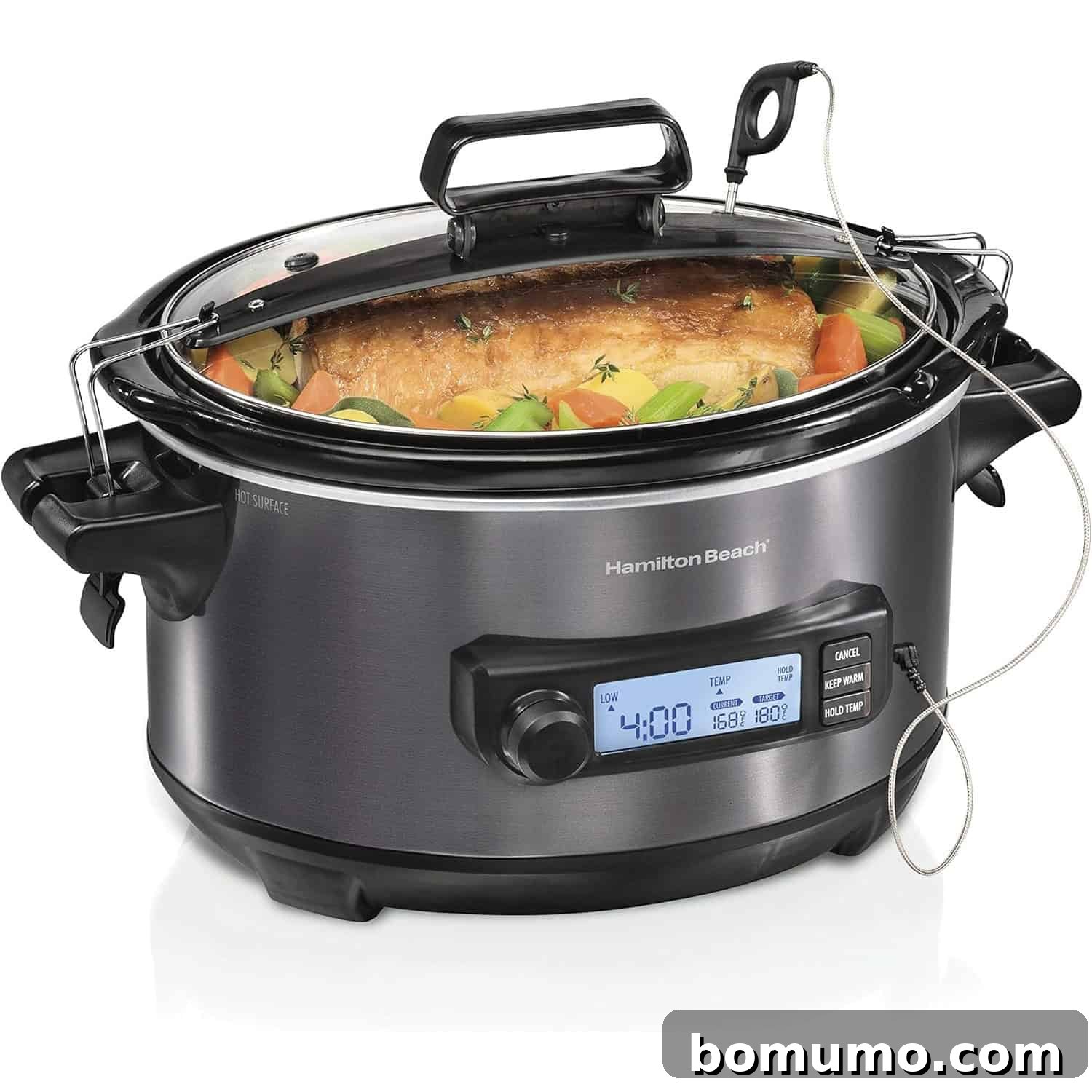A stainless steel Hamilton Beach slow cooker with a digital display, cooking a roast with vegetables inside, and a built-in meat thermometer probe attached.