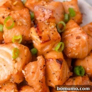 Crispy Honey Garlic Salmon Bites in the Air Fryer 13 Close-up of cooked salmon cubes seasoned with honey garlic sauce and garnished with chopped green onions.
